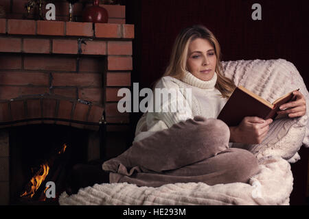 Ritratto di donna vicino al camino libro di lettura Foto Stock