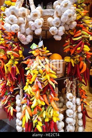 Mazzetti di aglio e colorati i peperoncini appesi a funi Foto Stock