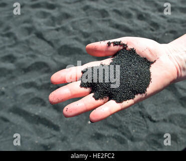 Sabbia nera sulla mano dalla grande isola di Hawaii Foto Stock