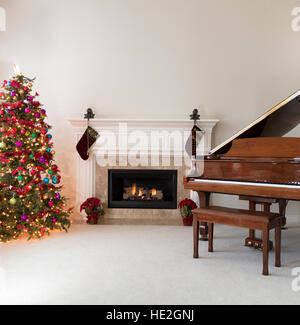 Soggiorno con camino incandescente, pianoforte e albero di Natale decorato per le feste Foto Stock