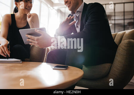 Ritagliato colpo di professionisti di aziende aventi una riunione in ufficio utilizzando Hall digitale compressa. I partner aziendali utilizzando computer touchscreen per il progetto Foto Stock