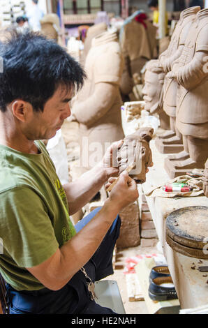 Operaio di Carver che produce guerrieri di terracotta e altri souvenir a Xian, Cina. Foto Stock