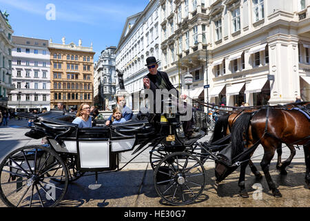 AUSTRIA, VIENNA - 14 Maggio 2016: Foto vista sui turisti su carrello con cavalli neri e driver in area centrale intorno al palazzo imperiale Hofburg Foto Stock