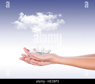 Da nuvole bianche, versando acqua sulle palme spruzzi in tutte le direzioni, di fronte a uno sfondo blu Foto Stock