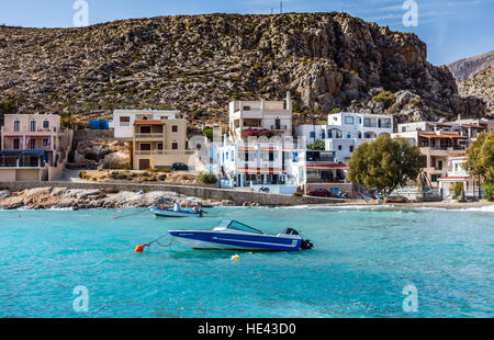 Piccolo Blu motoscafo sul mare aquamarine con uno stile Greco case baia circostante Foto Stock