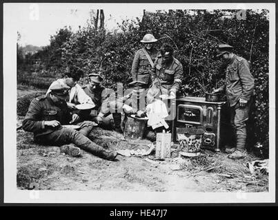 Questa fotografia cattura i soldati britannici, o "Tommies", gustando un pasto cucinato su una vera stufa durante la prima guerra mondiale. Fornisce un raro momento di tregua in mezzo alle difficoltà incontrate dai soldati durante il conflitto, sottolineando l'importanza del cibo e del calore nel mantenere il morale. Foto Stock