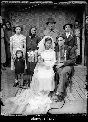 Un ritratto storico di nozze dall'Archivio Costică Acsinte, che mostra un matrimonio tradizionale rumeno a Ialomita. La fotografia d'epoca, scattata con la fotografia su lastre di vetro, riflette i costumi e le tradizioni culturali della Romania dell'inizio del XX secolo. Foto Stock