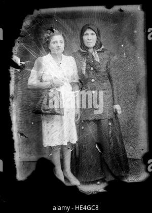 La «Doua femei» è una fotografia d’archivio di Costică Acsinte, scattata su una lastra di vetro a Ialomita, Romania. L'immagine raffigura due donne in abbigliamento tradizionale, catturando un momento della vita rurale in Romania all'inizio del XX secolo. Foto Stock