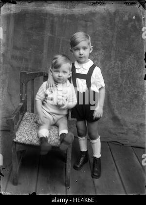 Una fotografia in bianco e nero di due bambini a Pasqua, scattata da Costica Acsinte a Ialomita, Romania. L'immagine dell'inizio del XX secolo cattura i ricordi dell'infanzia e le usanze culturali durante la celebrazione pasquale nella Romania rurale. Foto Stock