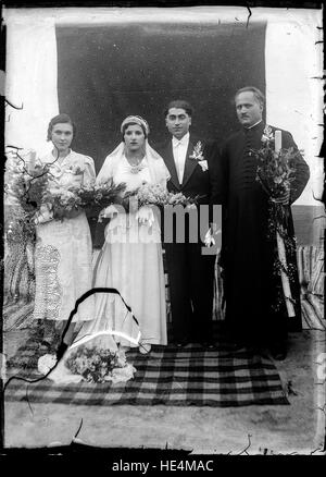 Una fotografia vintage su lastra di vetro di una sposa e di uno sposo di Ialomita, Romania, scattata all'inizio del XX secolo. L'immagine mette in risalto l'abbigliamento e i costumi tradizionali rumeni, riflettendo la cultura e le pratiche di matrimonio rumene rurali. Foto Stock