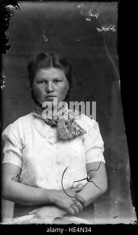 Un ritratto d'epoca di una donna rumena dell'inizio del XX secolo, catturato in abbigliamento tradizionale da Costica Acsinte. Questa lastra di vetro negativa riflette la cultura rurale della regione di Ialomita e il patrimonio rumeno. Foto Stock