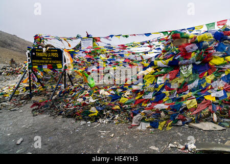 Preghiera tibetano flag sono avvolte intorno a un mucchio di pietre e il cartello sul thorong la, 5416 metri sopra il livello del mare, il pass fra la parte superiore di marsy Foto Stock