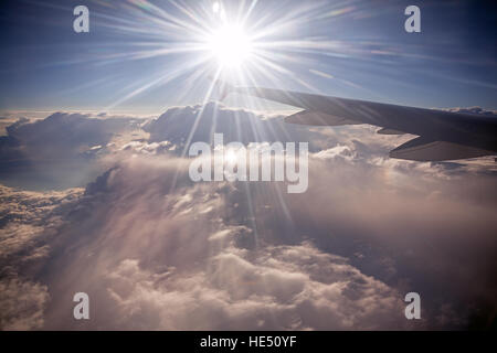 Ala del velivolo sullo sfondo di raggi di sole e nuvole. Antenna veloce trasporto, di viaggio e di concetto di viaggio. Guardando fuori attraverso la finestra di aereo. Foto Stock