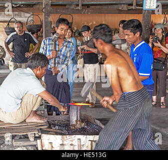 INLE, MYANMAR - Marzo 1, 2014: locale operai eseguire la forgiatura del ferro per la fabbricazione di souvenir in Inle, Myanmar Foto Stock