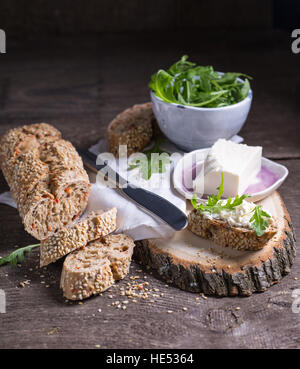 Pane con foglie di rucola e formaggio a pasta morbida per un sano pranzo Foto Stock