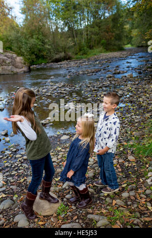 Tre bambini che sono fratelli in una candida foto all'aperto lungo le rive del fiume McKenzie in Oregon. Foto Stock