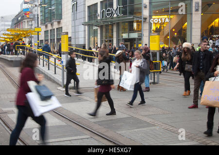Vita di tutti i giorni strade del centro città a Manchester, Regno Unito. Dicembre 2016. Le vendite prima del giorno di Santo Stefano iniziano in città con diversi rivenditori che pubblicizzano sconti per l'ultima settimana di shopping prima di Natale. Acquirenti, acquirenti che trasportano una borsa di acquisti e, in alcuni casi, molti articoli acquistati presso la vasta gamma di rivenditori speciali di alta classe all'interno e nei dintorni del tram del centro di Piccadilly. Foto Stock