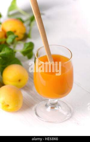 Succo di albicocche in vetro con frutti attorno Foto Stock