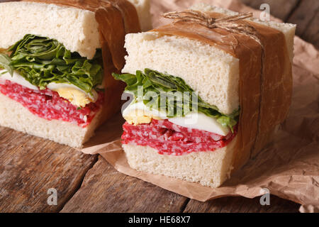 Panini rustici con salame, lattuga e uova vicino sul tavolo. Posizione orizzontale Foto Stock