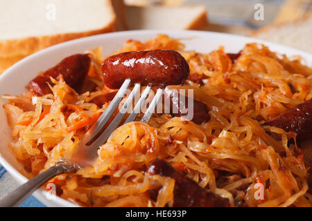 Stufati di cavolo con salsiccia macro in una piastra bianca. Posizione orizzontale Foto Stock