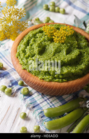 Purea di piselli verdi vicino fino in una ciotola di legno. In verticale Foto Stock