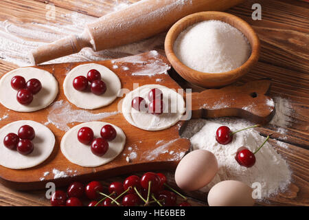 Il processo di cottura Gnocchi dolci con ciliegie close-up orizzontale. Foto Stock