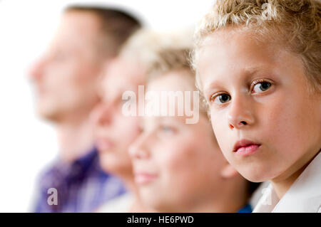 Vista laterale di una famiglia con due figli adolescenti. Figlio più giovane focus, seriamente, guarda nella telecamera. Foto Stock