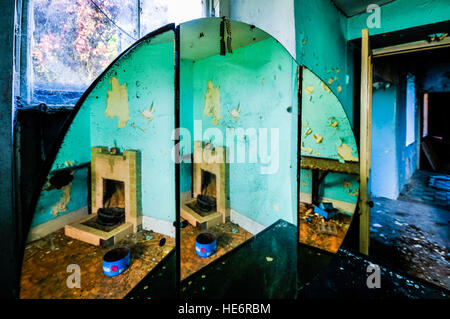 Specchio riflette un caminetto in camera da letto di un abbandonato casa colonica irlandese. Foto Stock