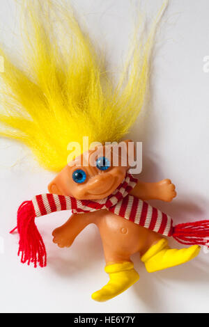 bambola troll con lunghi capelli gialli e occhi blu sciarpa a righe rossa e bianca e stivali gialli Foto Stock