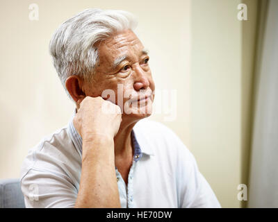 Ritratto di triste senior asian man mano sul mento, vista laterale. Foto Stock