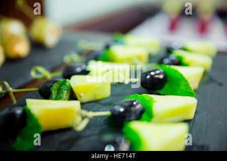 Blured soddisfare tartine con ananas e uva sulla tavola nera Foto Stock