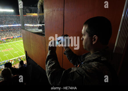 Florida Air National Guard affari pubblici specialista Master Sgt. Tom Kielbasa acquisisce video del Super Bowl XLIV dalla parte superiore del Sun Life Stadium di Miami, Florida, Febbraio 7, 2010. Quattro piloti dal 125th Fighter Wing (FW), Florida Air National Guard, basato a Jacksonville, aveva appena completato un cavalcavia stadium in F-15 Eagle fighter aircraft come parte del pregame attività. Lt. Col. Michael Birkeland, comandante di distacco 1, centoventicinquesimo FW, detto questo segna la prima volta che un Air National Guard unità ha eseguito un cavalcavia a un Super Bowl gioco. Tech. Sgt. Shelley Gill Foto Stock