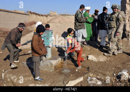 Membri della 777th Expeditionary bistecca di manzo Squadron e il 755th Expeditionary forze di sicurezza Squadron guarda come i bambini utilizzano il recente acqua fissa bene in un villaggio nei pressi di Bagram Air Field, Afghanistan, Gennaio 26, 2013. Acqua è di profonda importanza nell Islam, è considerato come una benedizione dal dio che dona e sostiene la vita, e purifica l'uomo e la terra. Senior Airman Chris Willis) Foto Stock