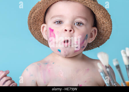 Adorabile ragazza Toddler coperto di vernice sulla pianura sfondo blu Foto Stock