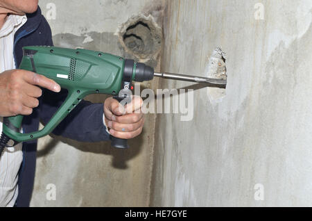 Uomo di mani del cesello elettrico della macchina e la realizzazione di un foro in un muro di cemento Foto Stock