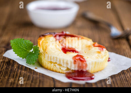 Cheesecake con salsa su un vecchio tavolo di legno come dettagliato di close-up shot (messa a fuoco selettiva) Foto Stock