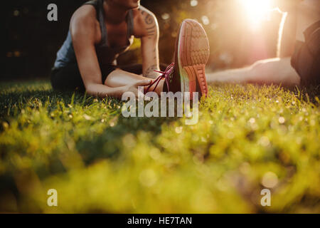 Ritagliato colpo di montare la giovane donna stretching al parco con l'uomo. Focus su piedi di femmina. Foto Stock