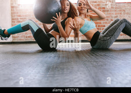 Due giovani donne che esercitano con palla medica in palestra. Ragazze che lavorano in palestra. Foto Stock