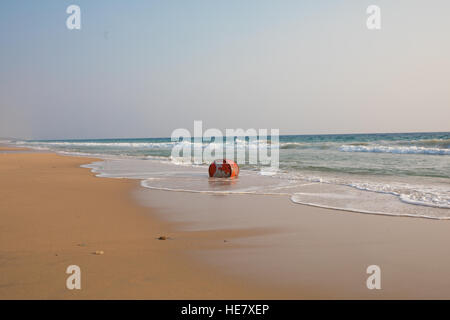 Un olio rosso tamburo viene lavato a terra presso la spiaggia di colore giallo Foto Stock