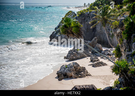 Spiaggia di Tulum e albero presso le rovine Maya con una vista. Autunno Caldo giorno con barche in background e cristalline acque blu lavaggio fino sulle spiagge di sabbia Foto Stock