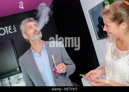 Uomo che cerca una sigaretta elettronica, respirazione fuori vapore Foto Stock