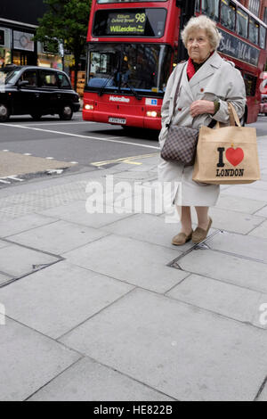 Una donna anziana che trasporta un amo Londra borsa riutilizzabile Foto Stock