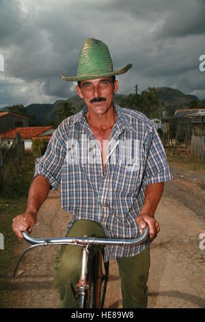 Uomo cubano indossando un cappello verde e in sella ad una bicicletta, Vinales, Pinar del Río Provincia, Cuba, America Latina Foto Stock