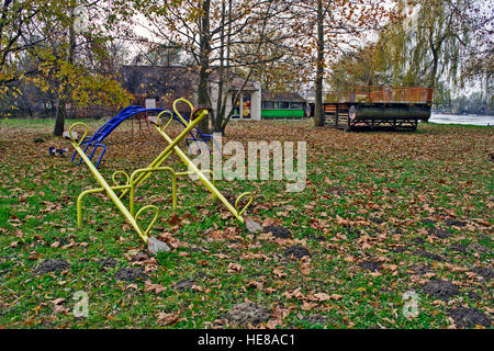 Un parco giochi vuoto sulla banca del fiume in autunno. Foto Stock