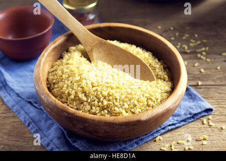 Organici di bulgur, cuscus materie del grano nel recipiente di ceramica close up - cibo sano ingrediente Foto Stock