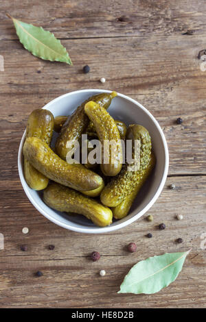 Pickles. Ciotola di cetriolini sottaceto (cetrioli) oltre rustico sfondo di legno Foto Stock