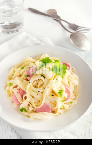 Alfredo tagliatelle con salsicce e verdi su piastra bianca - fatti in casa pasta cremosa Foto Stock