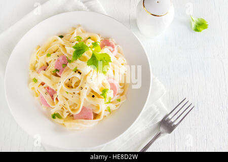 Alfredo tagliatelle con salsicce e verdi su piastra bianca - fatti in casa pasta cremosa Foto Stock