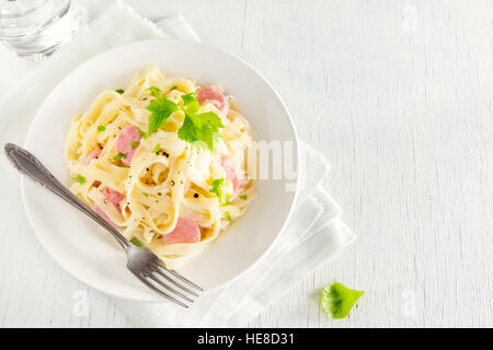 Alfredo tagliatelle con salsicce e verdi su piastra bianca - fatti in casa pasta cremosa Foto Stock