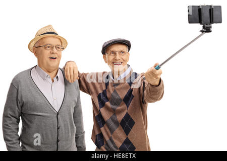 Allegro seniors prendendo un selfie con un bastone selfie isolati su sfondo bianco Foto Stock